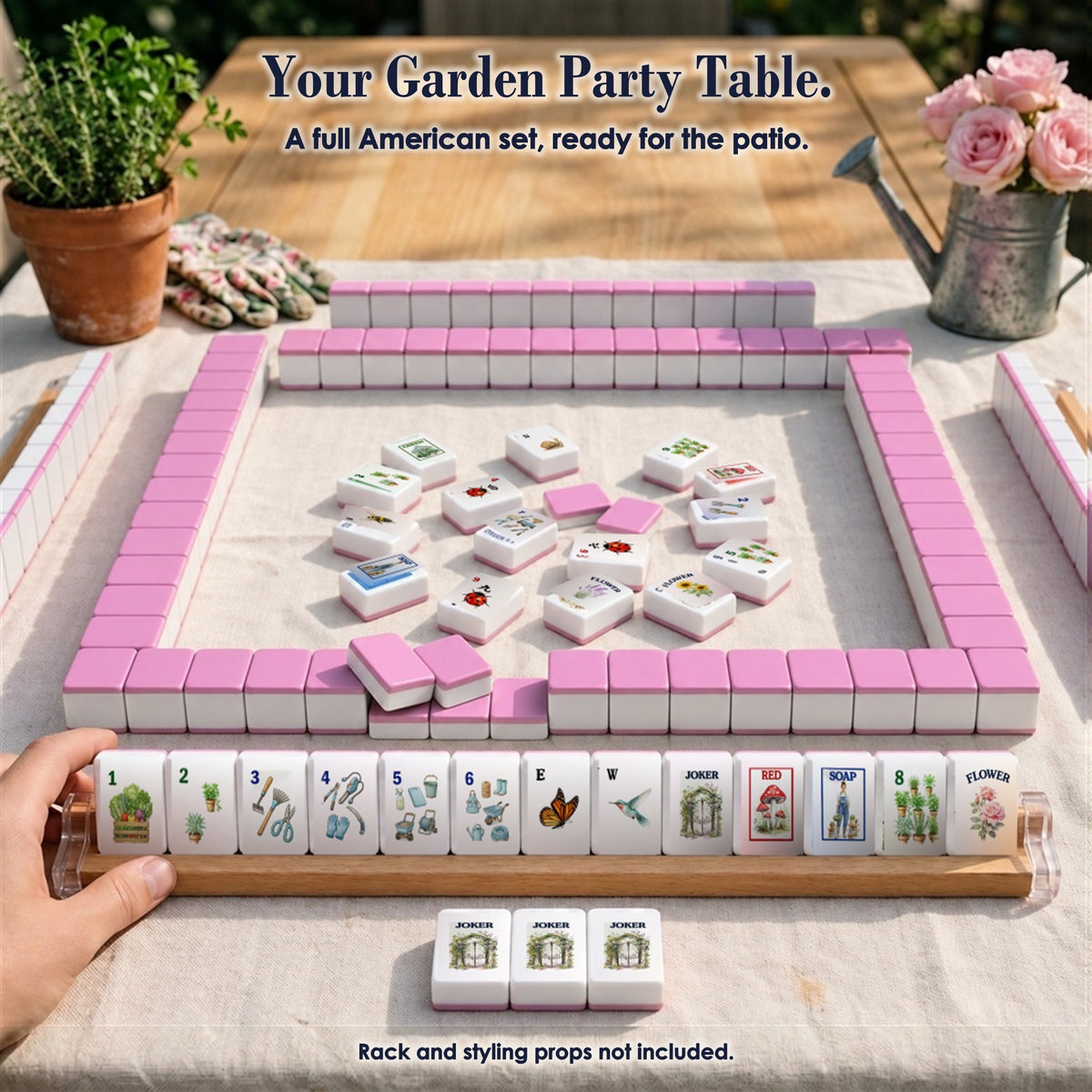 Garden mahjong game on a patio table: pink-backed tile walls, face-up tiles in the center, a rack of 13 tiles, three Jokers