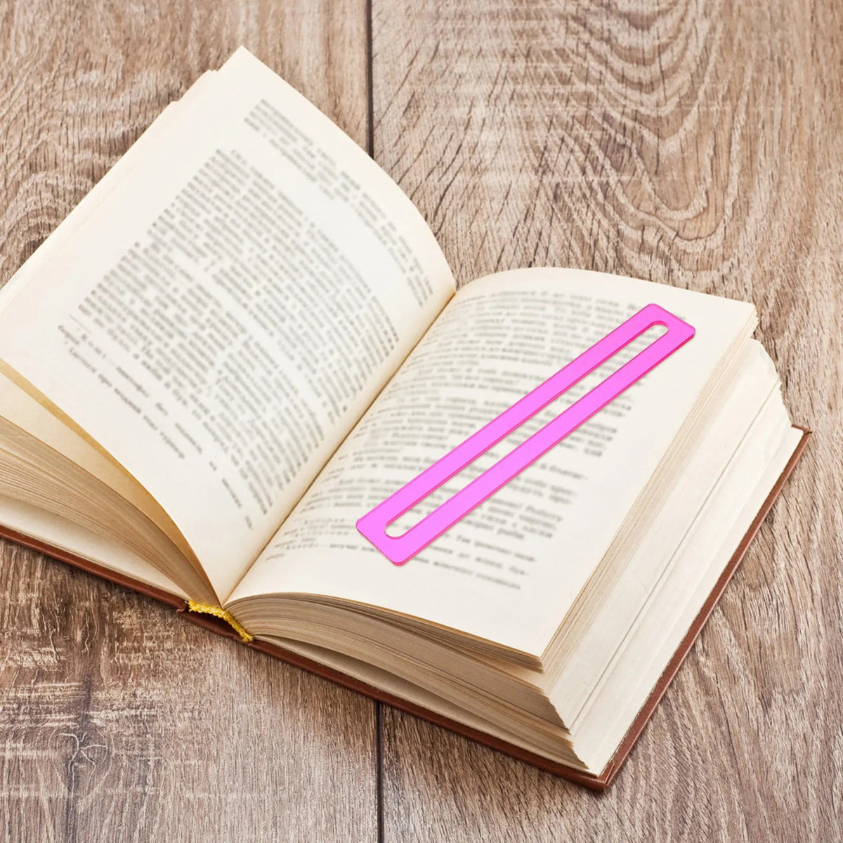 A pink line finder laid across one line of an open book