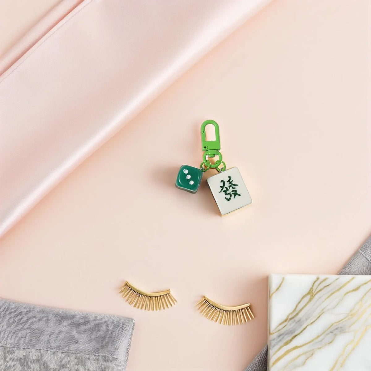 A single mahjong tile charm on a pink background