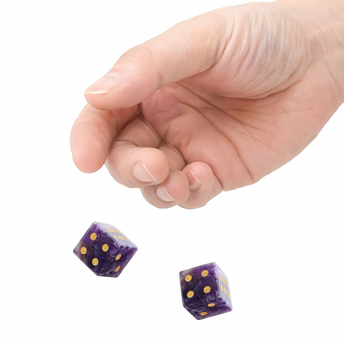A hand rolling two purple stone dice