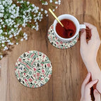 A hand setting a cup of tea on a mahjong tile print coaster
